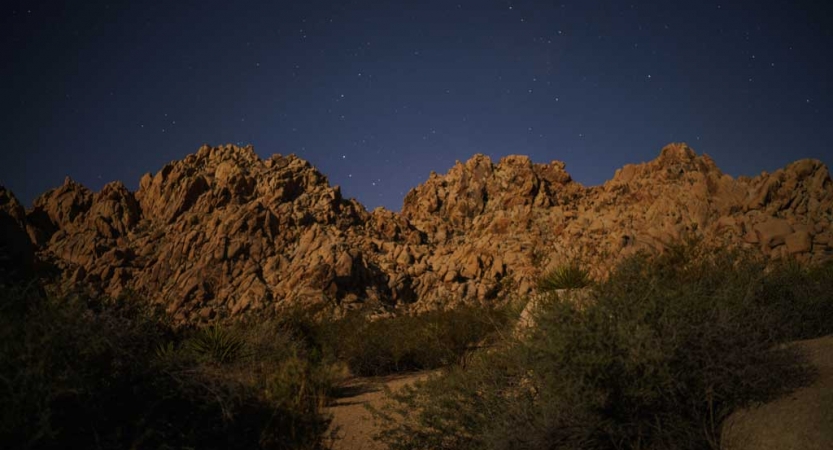 a large rock formation juts upwards towards the night sky, dotted with stars